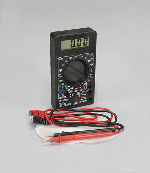 Photo of multimeter with black and red wire leads on top of white filter paper